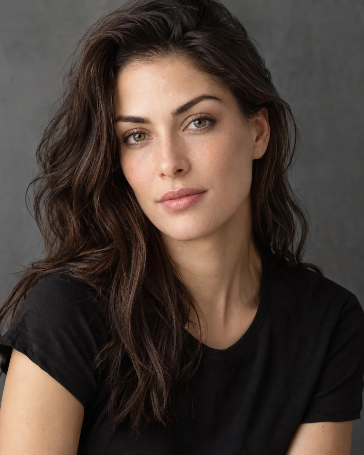 Retrato de una mujer con cabello suelto y camiseta negra sobre fondo gris